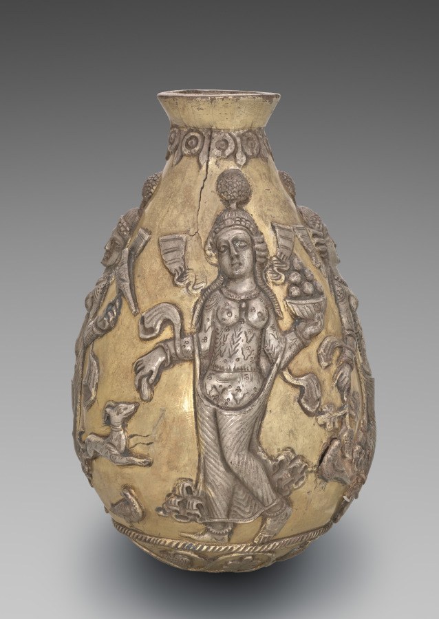 Silver vessel with high-relief figures: central standing woman in headdress surrounded by smaller attendants in bent-knee, raised-arm poses suggesting ecstatic