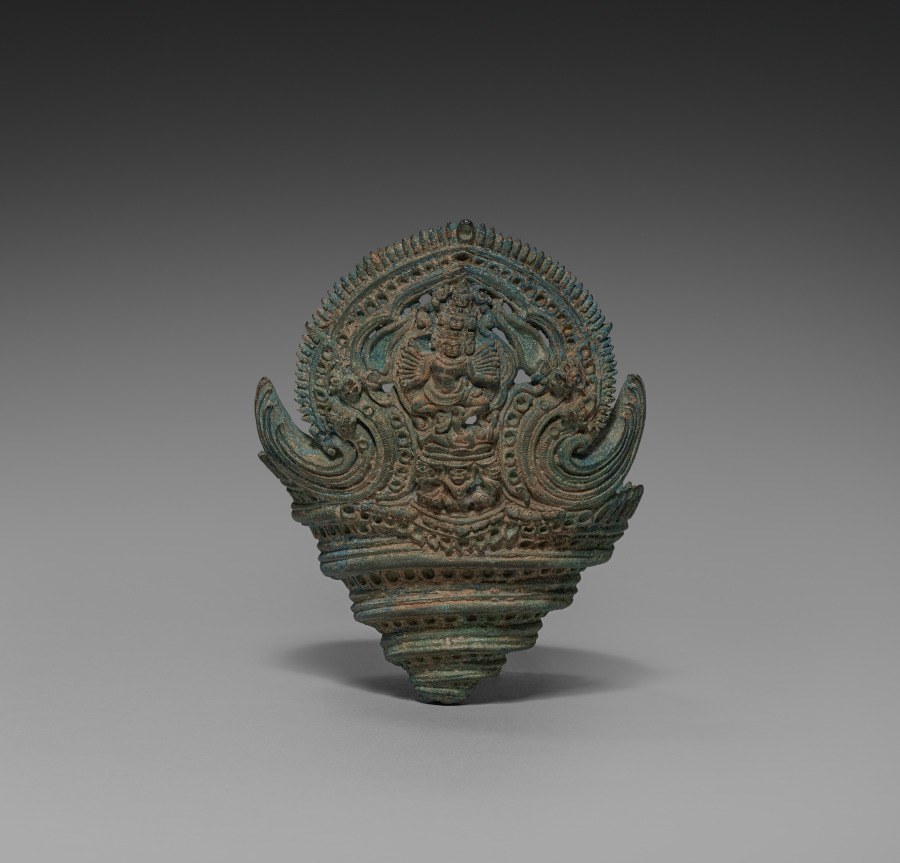 Bronze ritual conch ornament crowned with a carved dancing figure of Hevajra surrounded by spiral serpent forms, 12th-century Khmer.