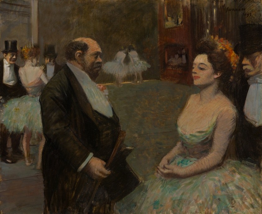 Bearded man and elegant woman in evening dress sit backstage at a theatre, watching an unseen performance with absorbed attention.