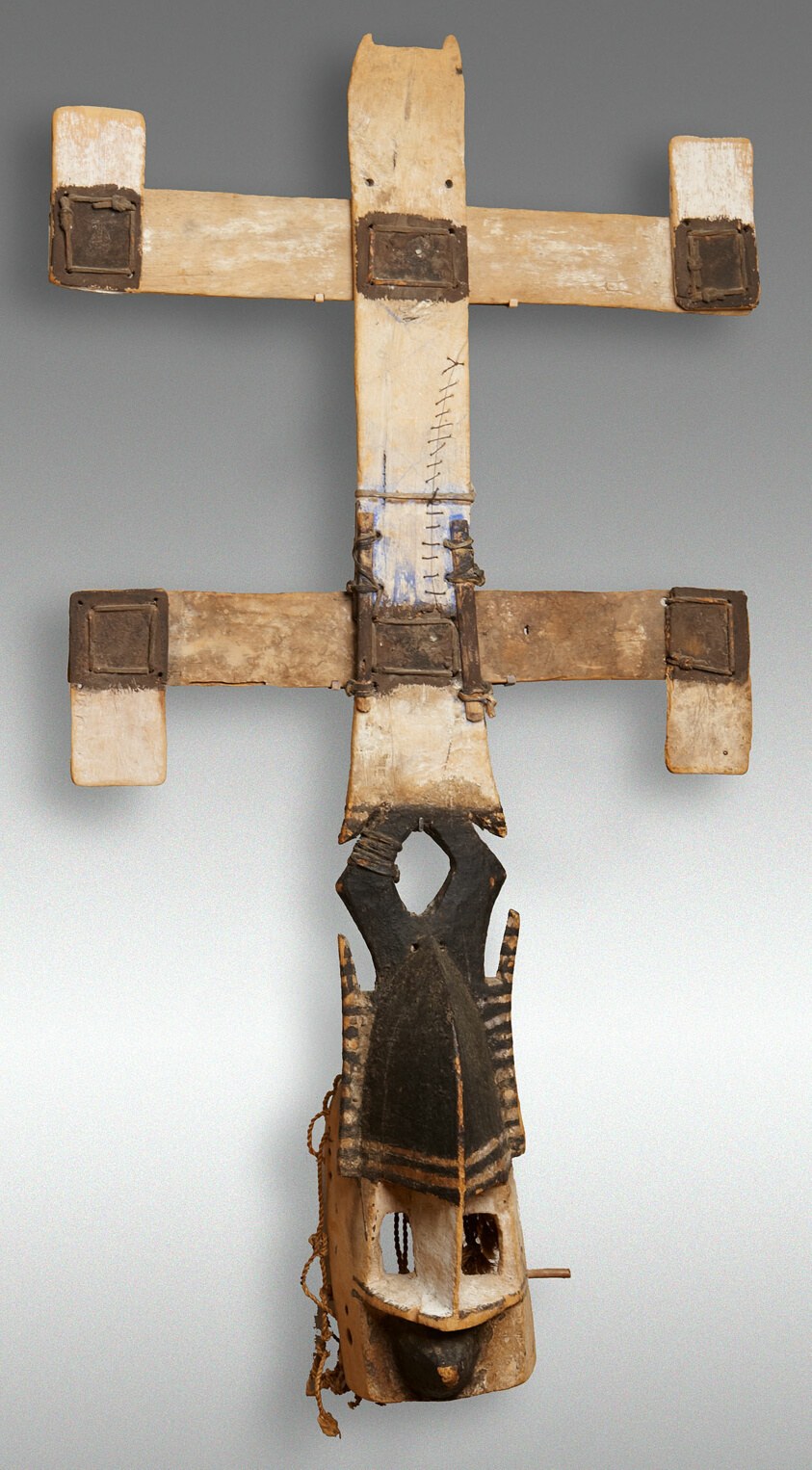 Dogon wooden face mask with upright horns and large rectangular openwork arms extending horizontally from carved central face.