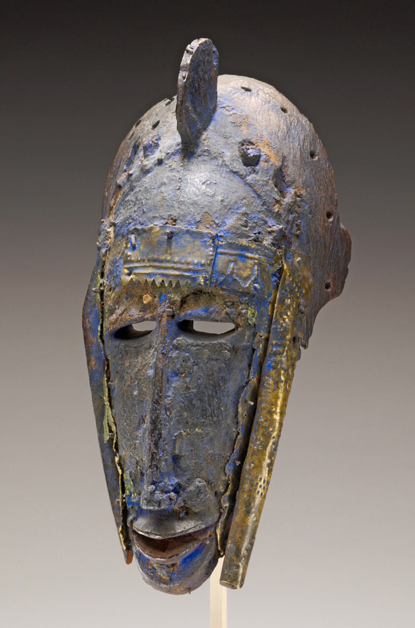 Wooden face mask with tall vertical crest, incised patterns, and copper and indigo inlay, darkened by age and wear.