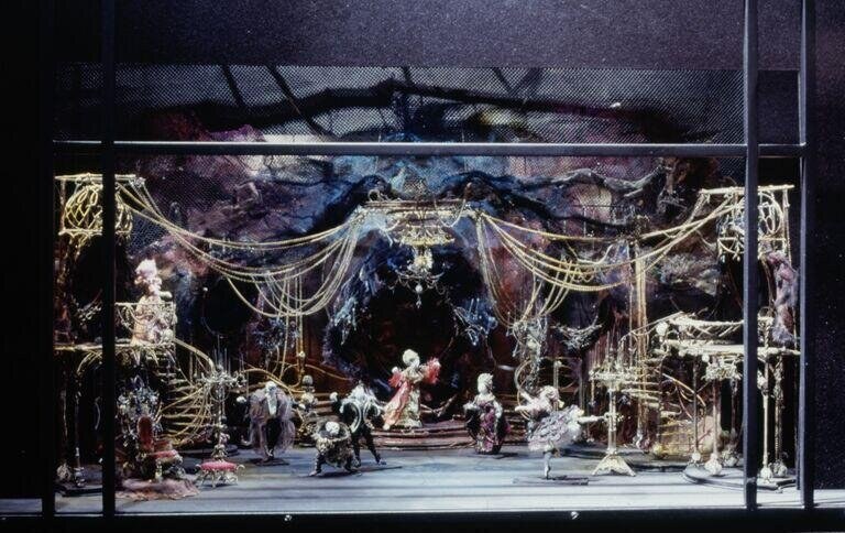 Scale model of an ornate 18th-century palace interior with gilt swags, classical columns, pale marble floor, and figures in courtly dress arranged symmetrically