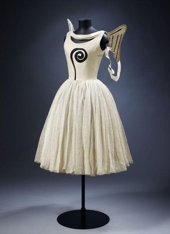 Cream sleeveless dance costume on a dress form with black spiral motif, pleated tulle skirt, and matching gauze shawl.