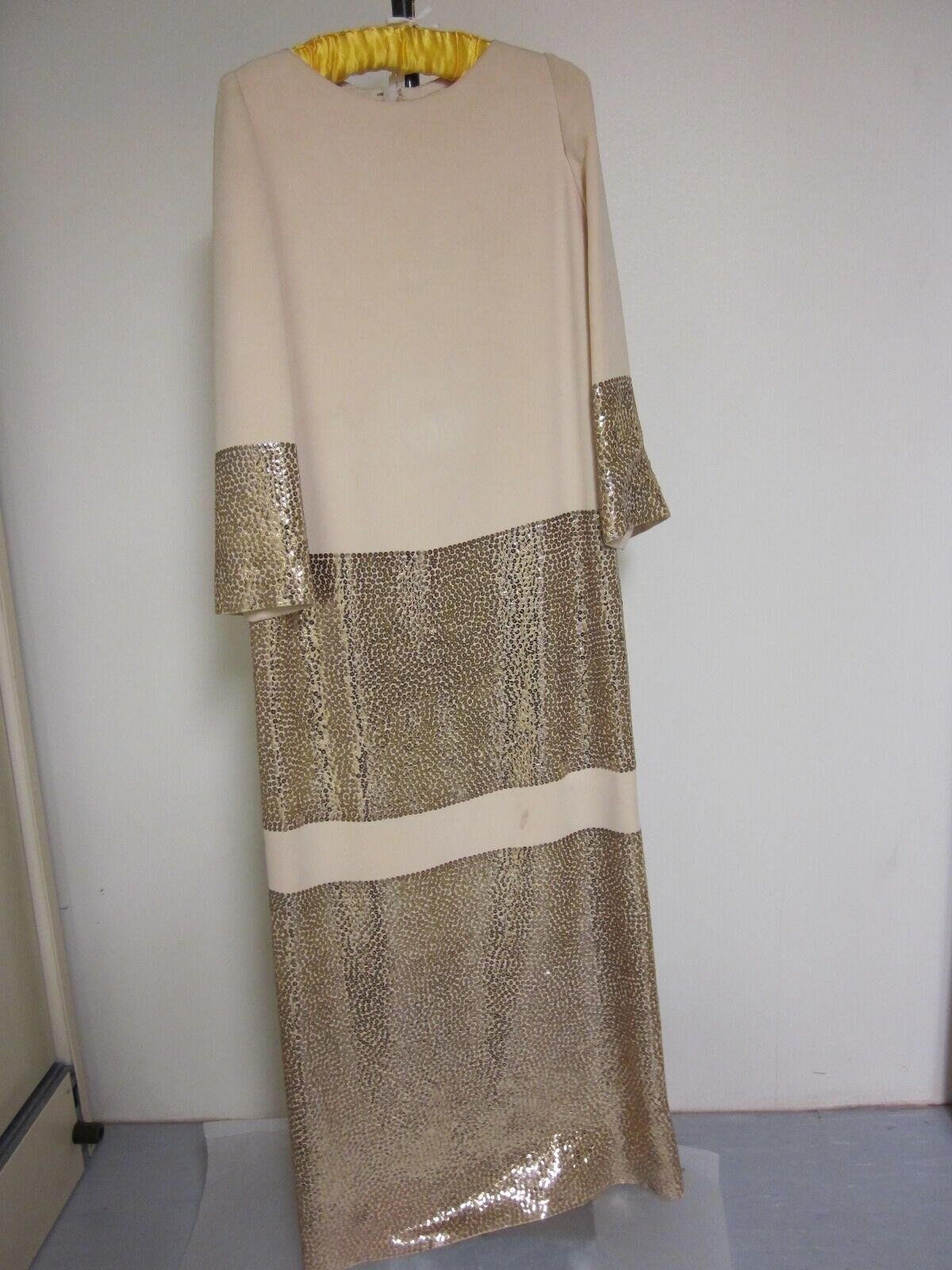 Cream and gold sequined evening dress on a hanger, alternating horizontal bands of sequins and silk.