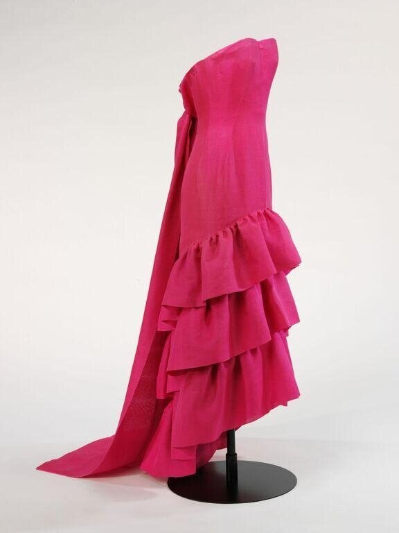 Fuchsia evening gown with fitted bodice and cascading tiered ruffles on dress form, photographed against neutral background.