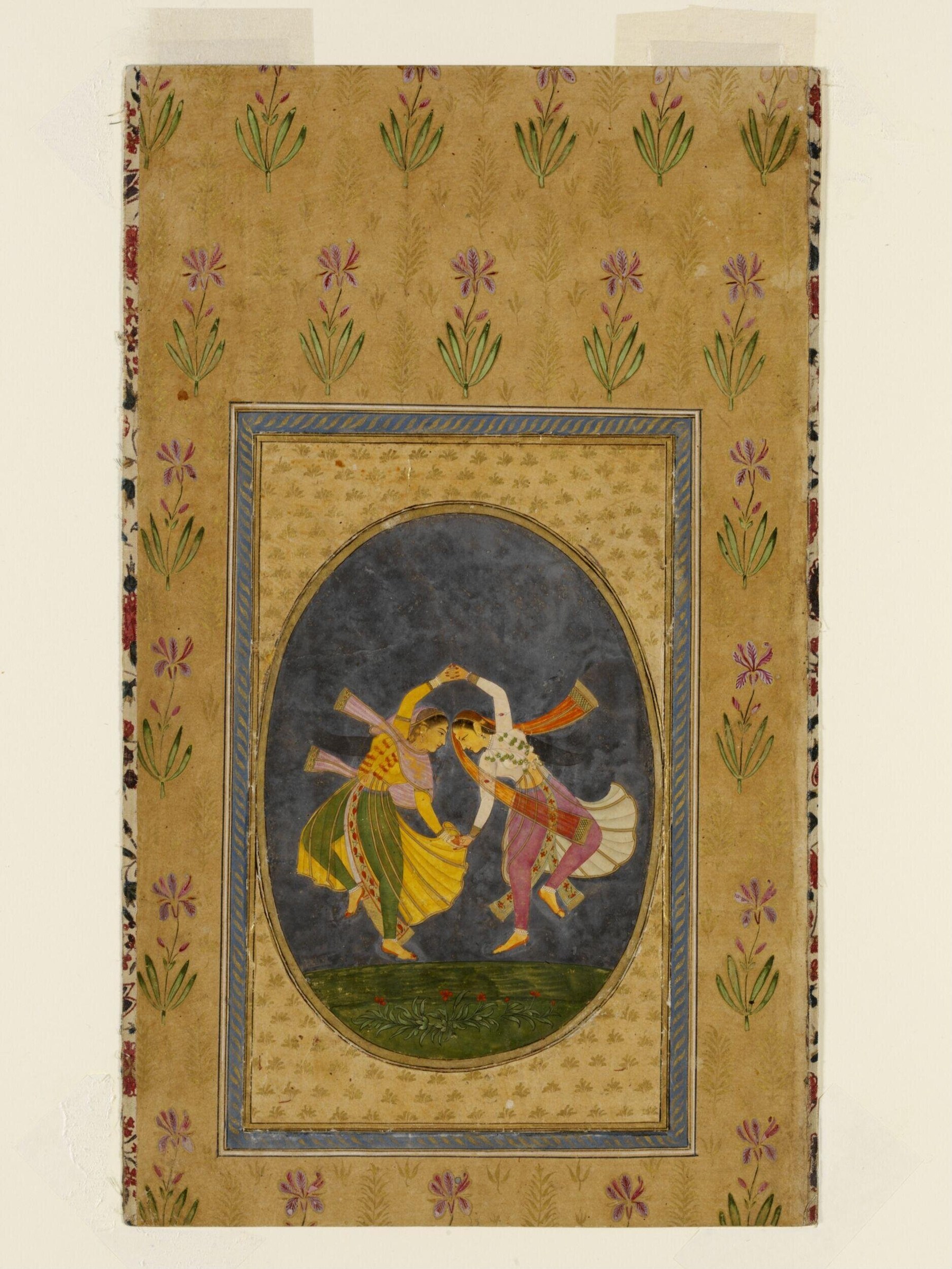 Two jewelled court musicians in profile playing wind instruments against a dark background, set in a gold-leaf frame with floral borders.