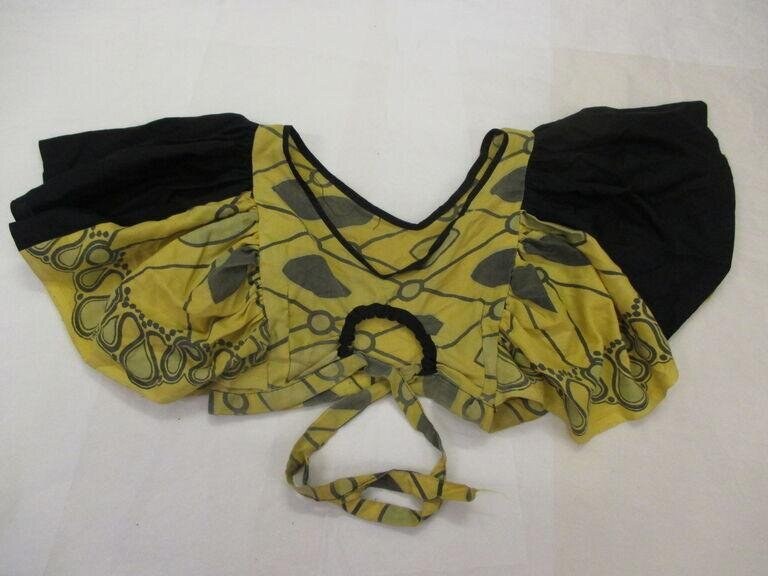 A yellow and black patterned dance costume laid flat, consisting of a voluminous draped garment with geometric designs and black fabric components.