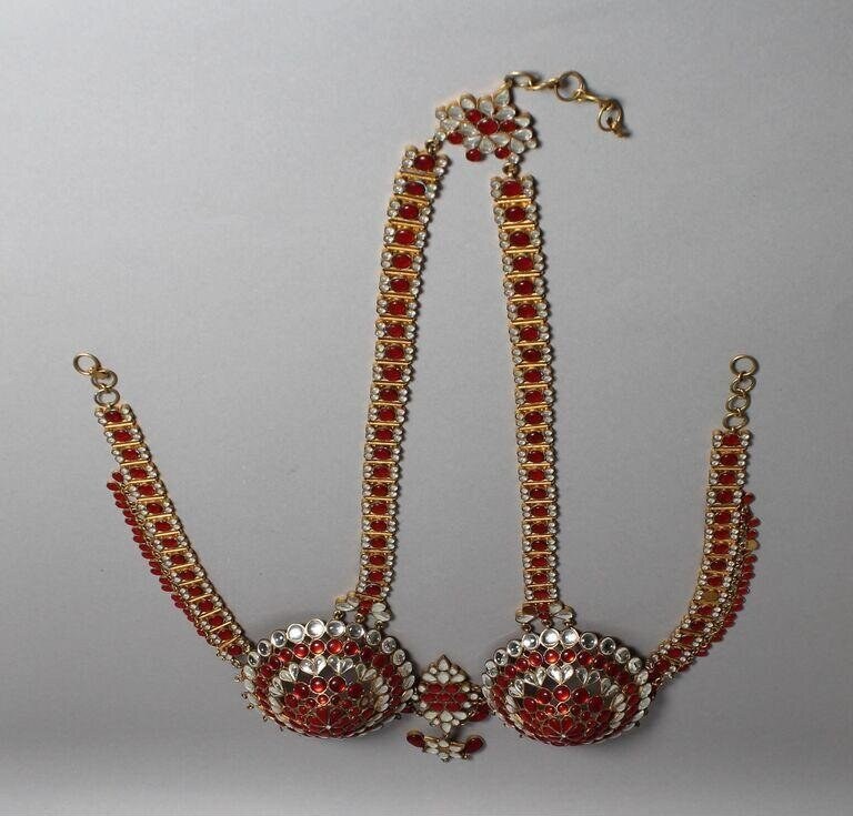 Ornate theatrical jewelry with U-shaped arrangement of red gemstones in gold filigree, with large jeweled medallions at junction points.