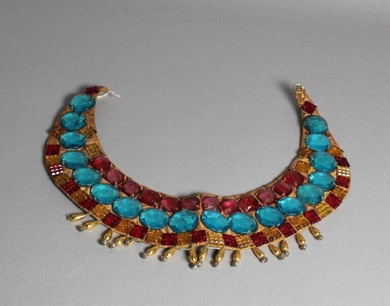 Gold filigree pectoral ornament with alternating turquoise and red cabochon stones and hanging pendant tassels