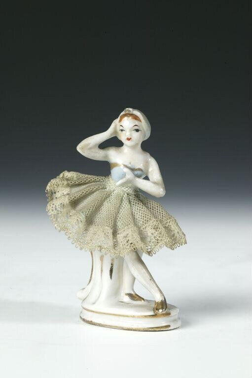 Small porcelain figurine of a ballerina in classical pose, wearing white bodice and cream lace tutu, circa 1920.