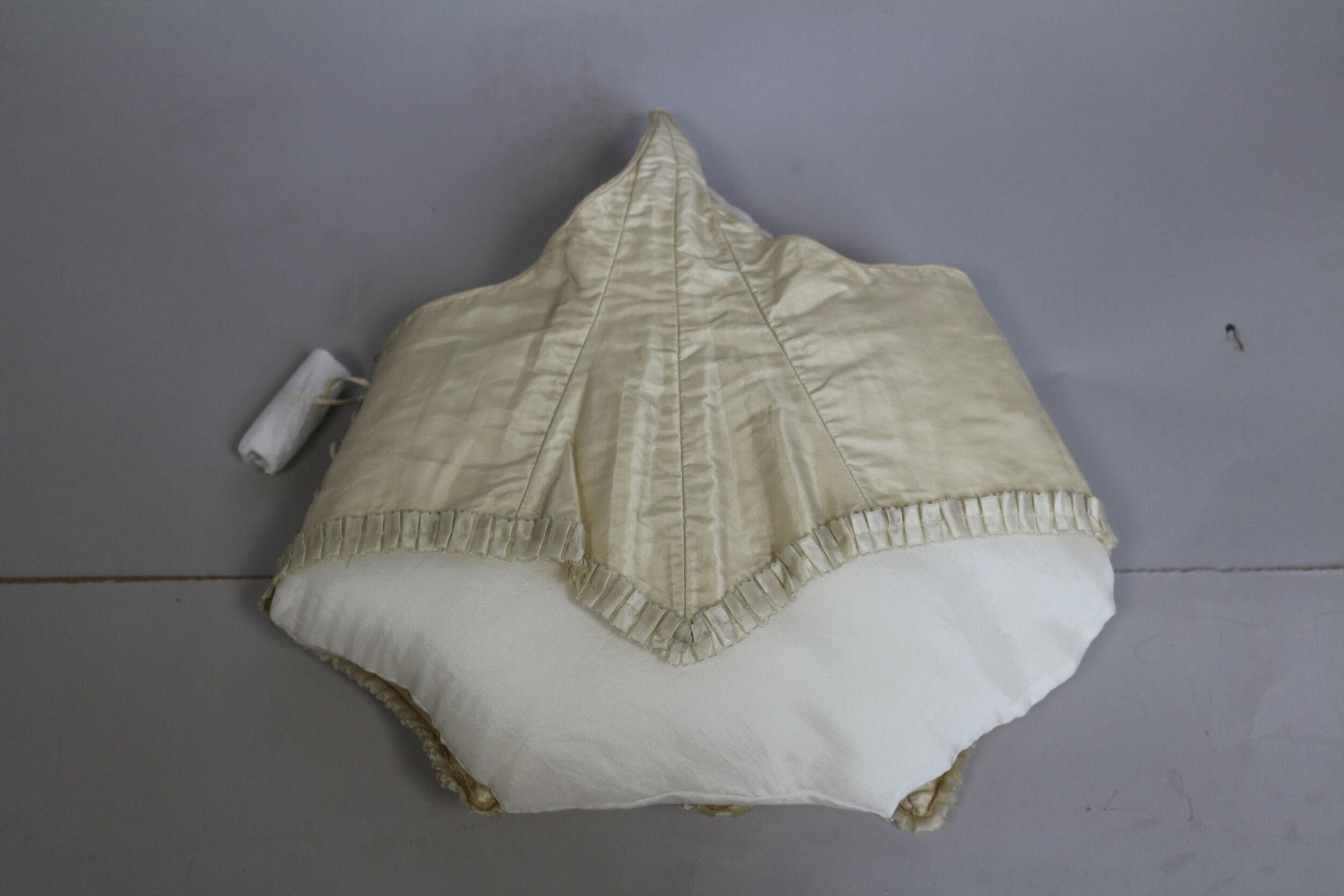 Cream and white fabric costume laid flat, with a cone-shaped quilted top and gathered bubble skirt.