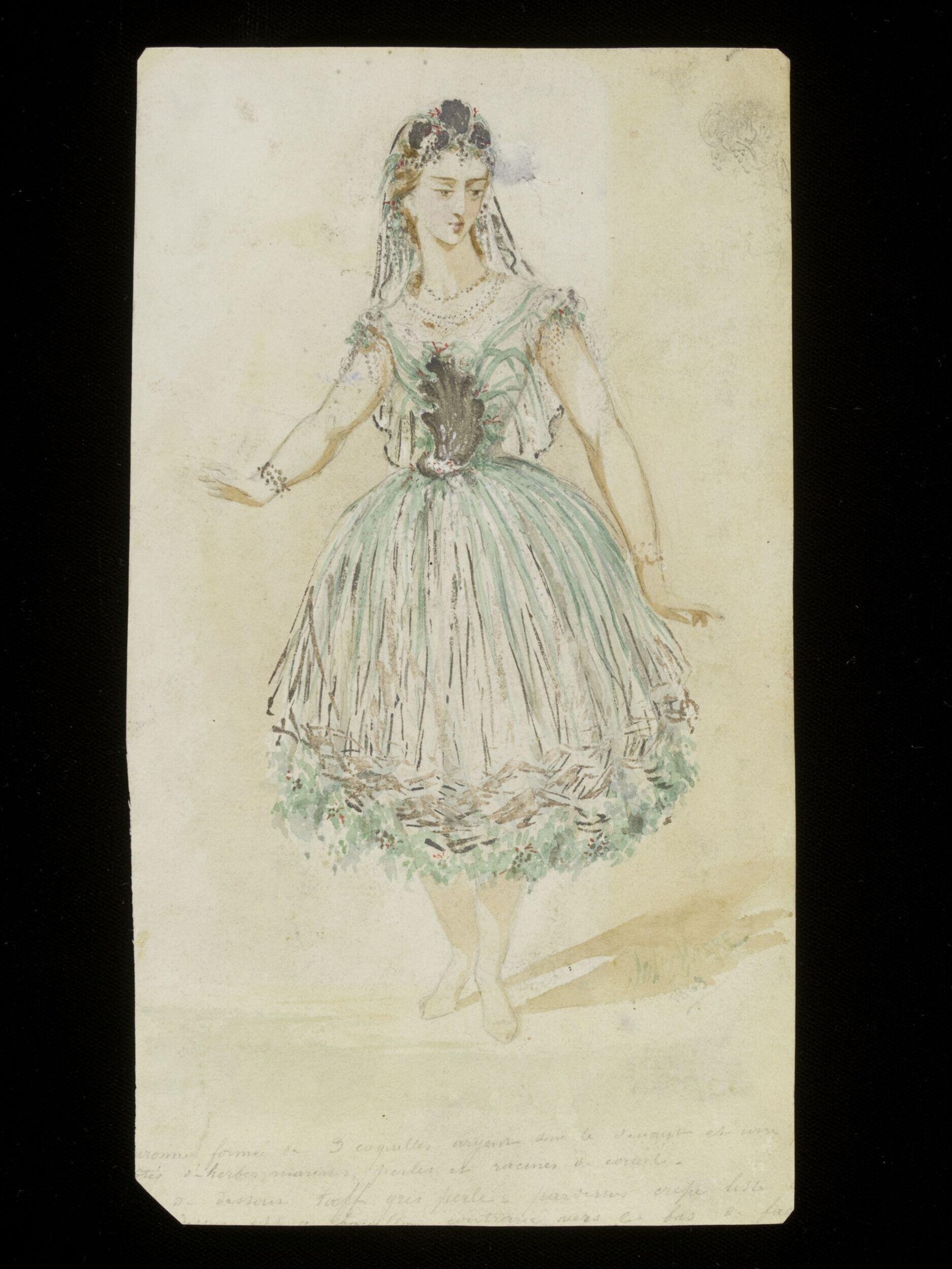 A young woman in a pale green Romantic-era ballet costume with a full pleated skirt, beaded bodice, veil, and foliage trim, standing in repose.