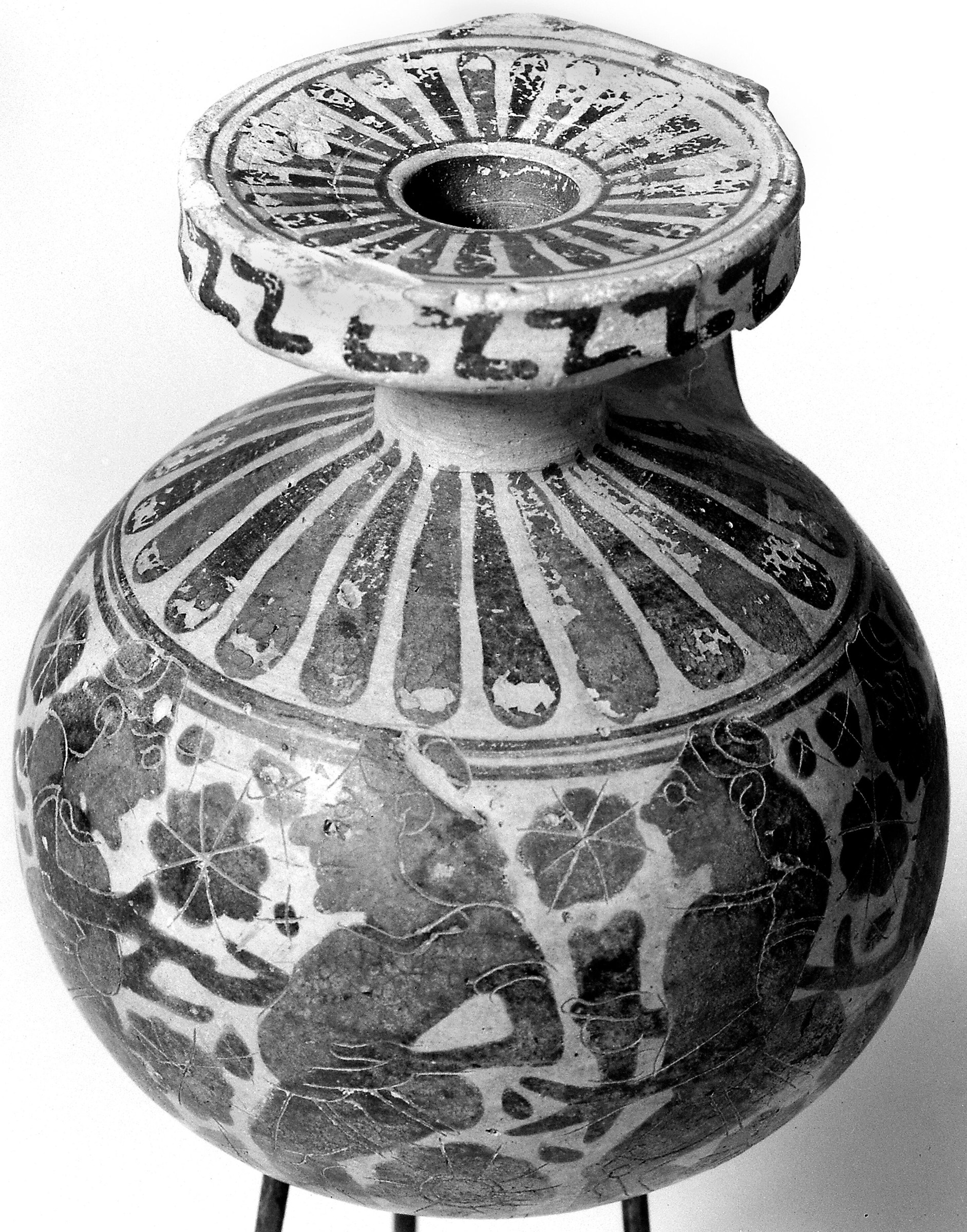 Ancient Greek ceramic vessel decorated with six padded dancers and a siren in profile, rendered in red-figure technique.