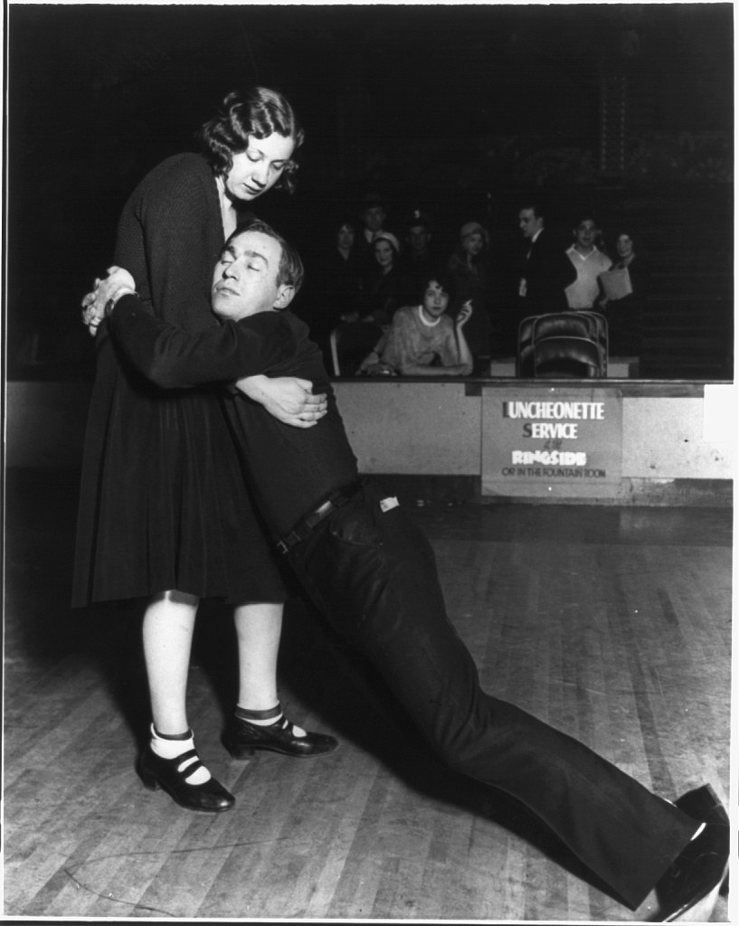 Black-and-white photograph of a male dancer collapsed against his female partner during a marathon dance competition, 1930.