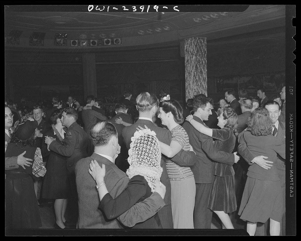 Crowded black-and-white photograph of couples dancing closely in closed position at a 1940s Harlem ballroom, bodies overlapping, men in suits, women in