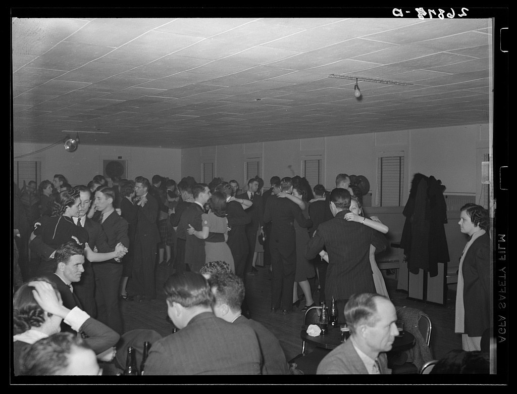 Black-and-white photograph of a crowded dance hall filled with formally dressed men and women dancing and socializing in 1939.