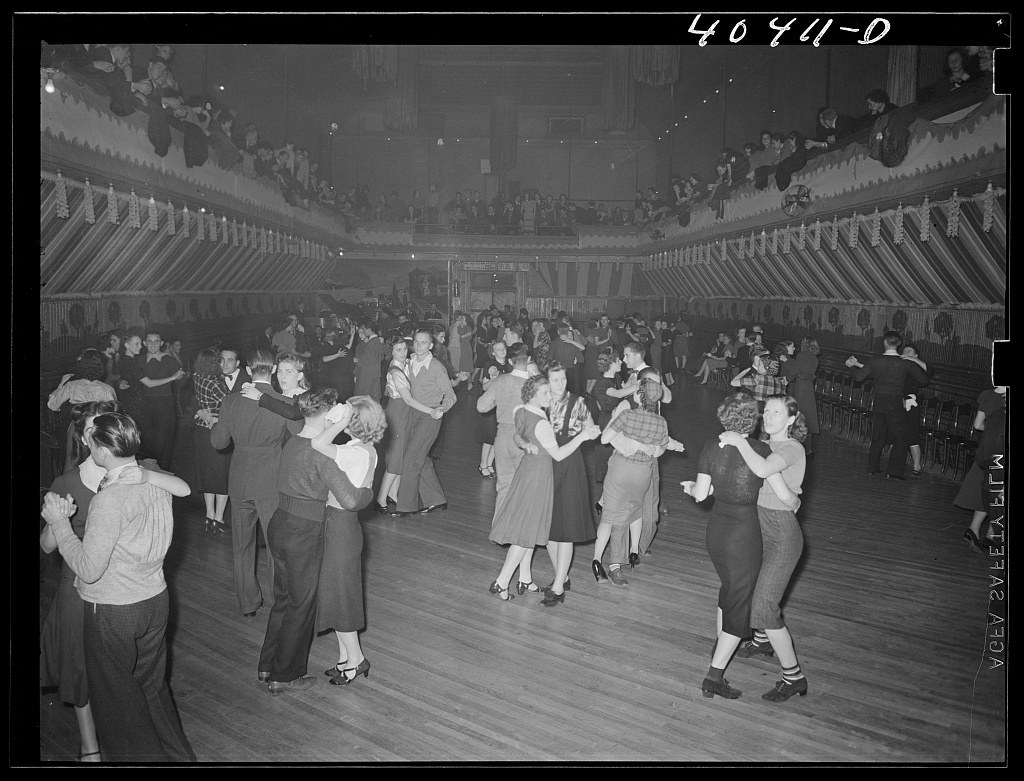 Overhead photograph of a crowded dance hall floor with dozens of couples dancing in close embrace under artificial light, 1938.