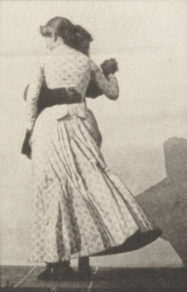 A man and woman in formal dress waltz together in a studio, her long white skirt billowing mid-turn.