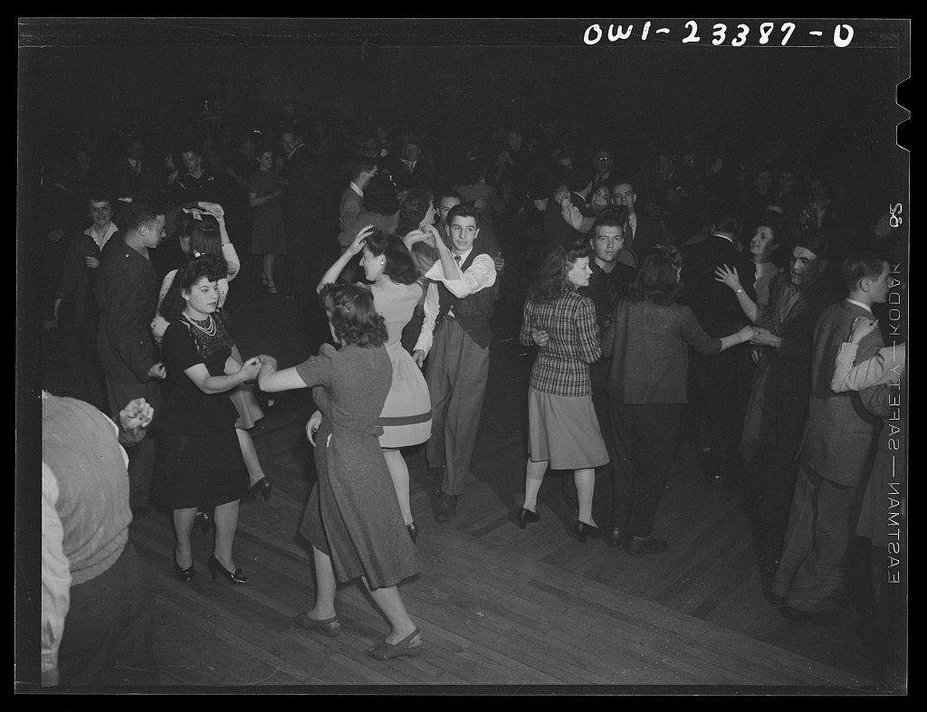 Crowded ballroom filled with couples dancing and socializing in suits and dresses, 1943